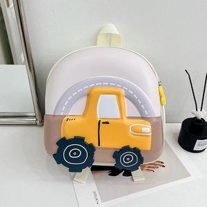 Detailed view of the 3D yellow tractor design on a cream-colored kid's hardshell backpack