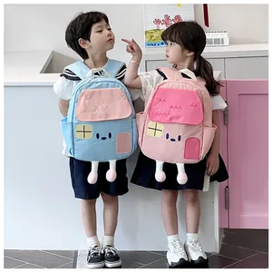 Detail of cute house-shaped kids backpacks in blue and pink with 3D leg features