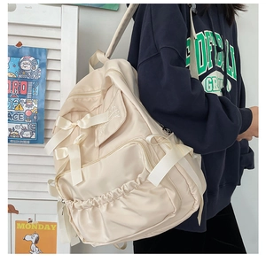 Dettaglio dello zaino beige per studentesse con fiocchi e tasche laterali capienti
