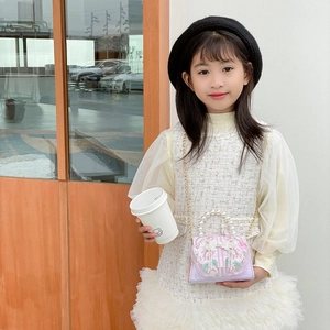 Sac à main pour fille en satin avec perles, broderies et chaîne porté par un mannequin