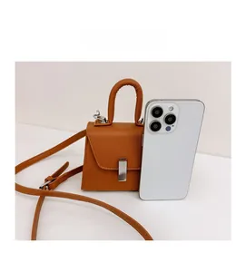 Detail view of mini brown crossbody bag showing size comparison with a smartphone
