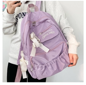 Dettaglio dello zaino scolastico viola con fiocchi bianchi e tasche laterali a pieghe