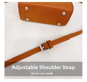 Detail of adjustable shoulder strap with silver buckle on brown textured leather kids bag