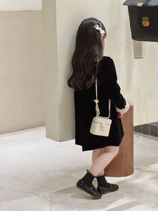 Detail of white quilted chain box bag with gold logo on child's black velvet dress