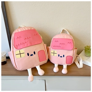 Detail view of two cute house-shaped backpacks for kids in different sizes on a desk