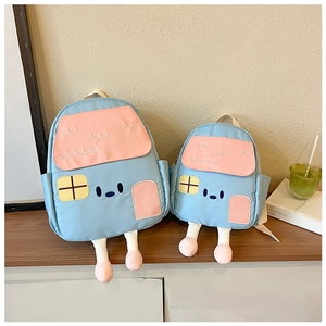 Detail of house-shaped backpacks in two sizes with plush legs on a wooden shelf