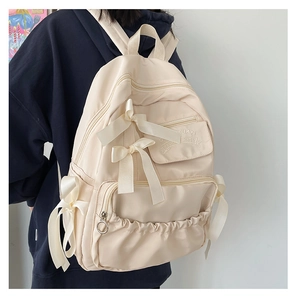 Dettaglio dello zaino color crema con fiocchi di seta e trama del tessuto in nylon
