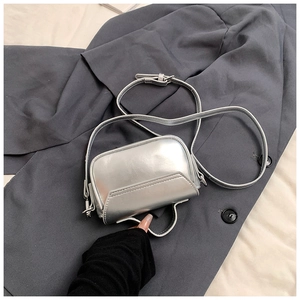 Detail of silver metallic mini handbag with top handle and adjustable shoulder strap