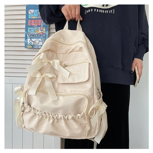 Dettaglio dello zaino bianco panna con fiocchi di seta e tasche multiple con zip