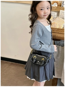 Detail of vintage black oil wax leather mini crossbody bag with gold buckle on a child model