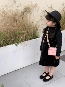 Detailed view of a pink quilted mini chain bag paired with a black velvet dress for girls