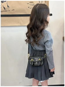 Rear view of a girl wearing a black oil wax leather crossbody bag with gold buckles