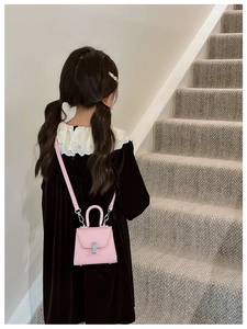 Pink mini crossbody bag for kids with leather texture and silver lock shown on a model