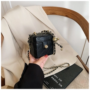 Detail of black quilted leather bag with gold floral clasp and metal chain strap