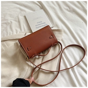 Détail du mini sac en cuir marron texturé avec coutures contrastées et anneau métallique