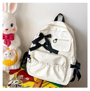 Dettaglio dello zaino in nylon bianco con fiocchi di raso neri e cerniere ad anello
