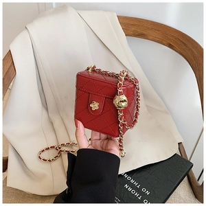 Detail of red quilted mini box bag with gold chain and flower-shaped metal clasp