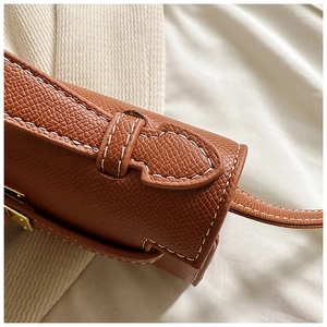 Détail d'un sac en cuir marron grainé avec coutures blanches contrastées et boucle dorée