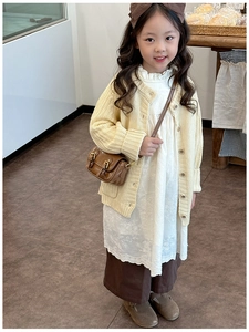 Detail of vintage cream knitted cardigan and floral embroidered dress for girls