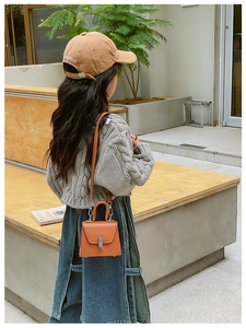 Outdoor street view of a child wearing a bright orange lychee leather crossbody bag
