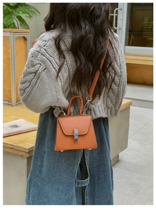 Rear view of a child wearing a caramel mini trapezoid crossbody bag in a cafe setting