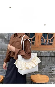 Detail of a large cream canvas tote bag featuring decorative ruffled pleats and ruffles