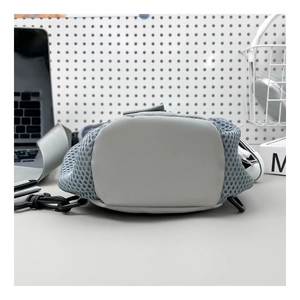 Detail of grey mesh crossbody bag with durable metal clip on a modern desk setting