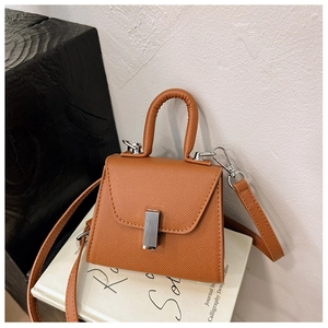 Detail of a brown trapeze kids bag with cross-grain texture and silver metal clasp