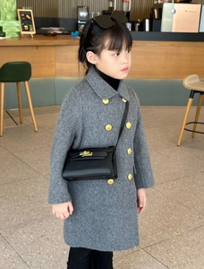 Détail de boutons ronds dorés sur un manteau en laine grise pour enfant de style luxe