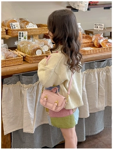 Detail of pink mini satchel bag for girls with gold buckles in a cozy bakery setting