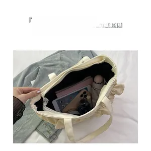 Detail showing the large capacity and internal compartments of the cream nylon bucket bag