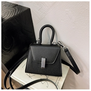 Detail of black mini crossbody bag with silver metal lock on textured faux leather