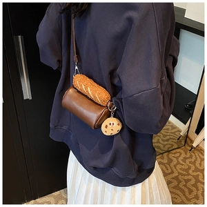 Vue détaillée d'un sac cylindrique marron avec pendentifs en peluche sur un modèle