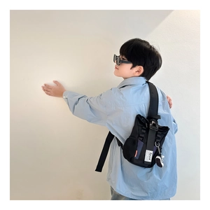 Detail of black nylon kids chest bag featuring a sneaker charm and mesh side pocket