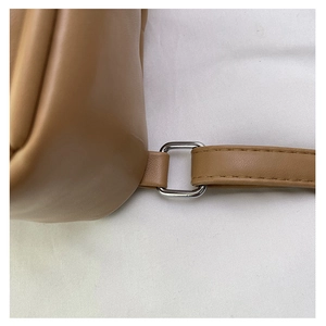 Detail of a brown leather backpack showing a silver adjustable metal buckle on the strap