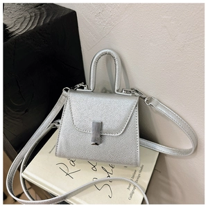 Detailed macro of a mini silver metallic handbag with a chic square lock and leather texture