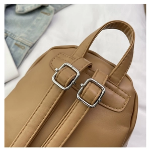 Close-up of brown PU leather backpack with silver buckles and fine stitching details
