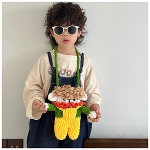 Detail of hand-crocheted cartoon sheep bag with green strap on a child model