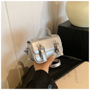 Close-up of silver oily leather texture and double buckle detail on the mini crossbody bag