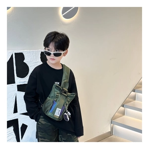 Detail view of military green kids chest bag with side mesh pocket and decorative shoe pendant