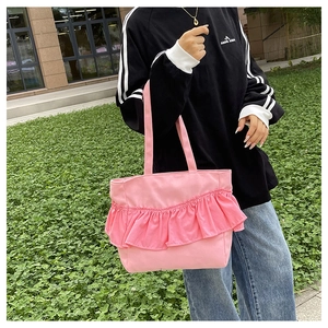 Close-up of pink canvas tote bag featuring ruffled edge details and long shoulder straps