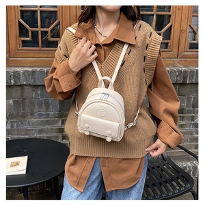Close-up of cream PU leather mini backpack with metal zippers and front pocket