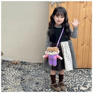 Detail of a handmade purple crochet sheep shoulder bag worn by a young girl in a park