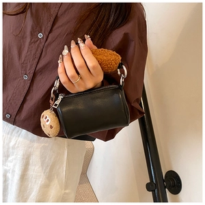 Détail d'un sac cylindre noir avec poignée en sherpa marron et breloque biscuit en peluche