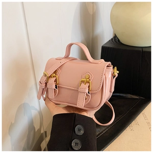 Detail of pink glossy patent leather mini bag with double gold buckle straps