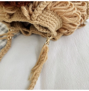 Detailed close-up of a handmade crochet sheep bag with tassels and metallic lobster clasp