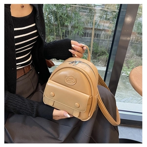 Detail view of light brown mini backpack showing textured leather and front flap pocket