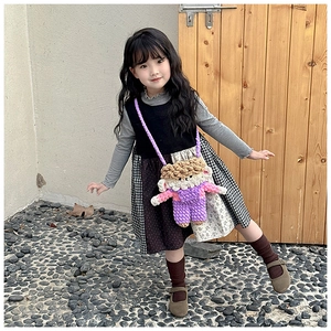 Detail of a purple crochet doll-shaped crossbody bag on a little girl outdoor outfit