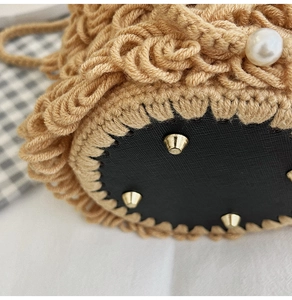 Detail of crochet bucket bag featuring leather base and golden protective metal feet