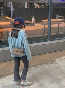 Détail du mini sac bandoulière gris avec fermoir doré tournant et design classique